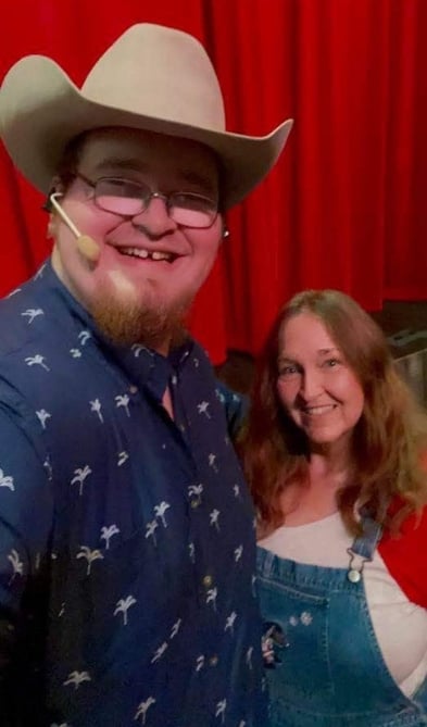 A guest and a performer take a photo looking at camera.